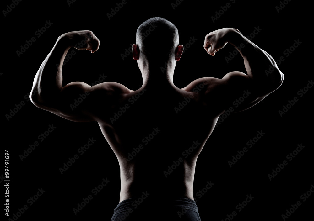 Fototapeta premium bodybuilder demonstrates biceps back view on a dark background