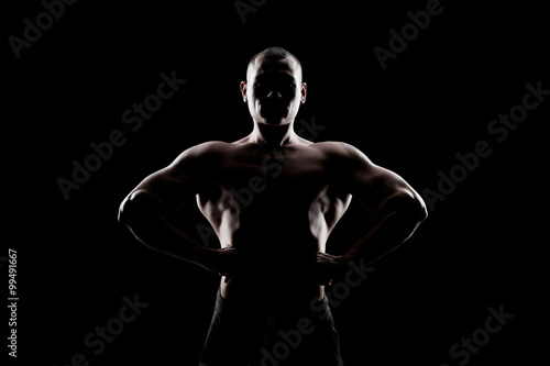 bodybuilder demonstrates biceps on a dark background