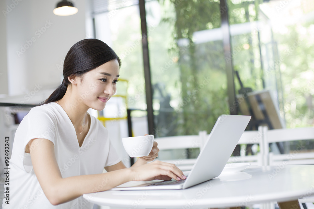 Happy young woman using laptop in coffee shop Happy young woman using laptop in coffee shop