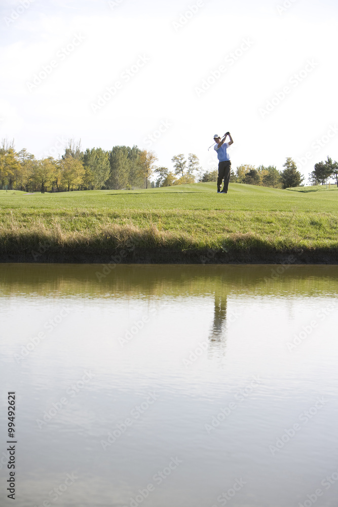Fototapeta premium Man swinging golf club on golf course