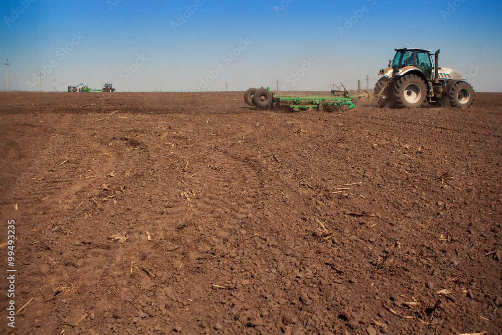 view of tractor seeder sowing in ploughed field view of tractor seeder sowing in ploughed field