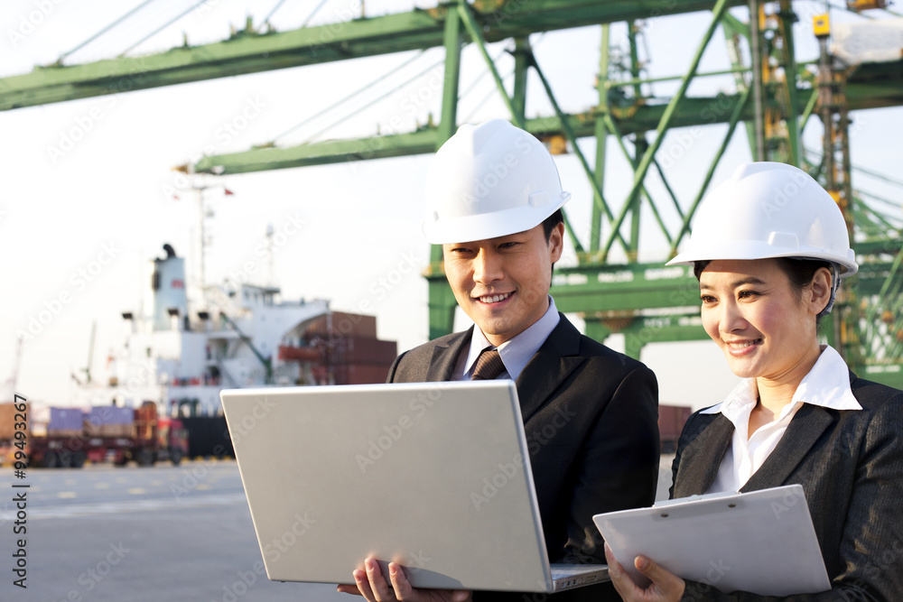businesspeople using a laptop at a shipping port businesspeople using a laptop at a shipping port