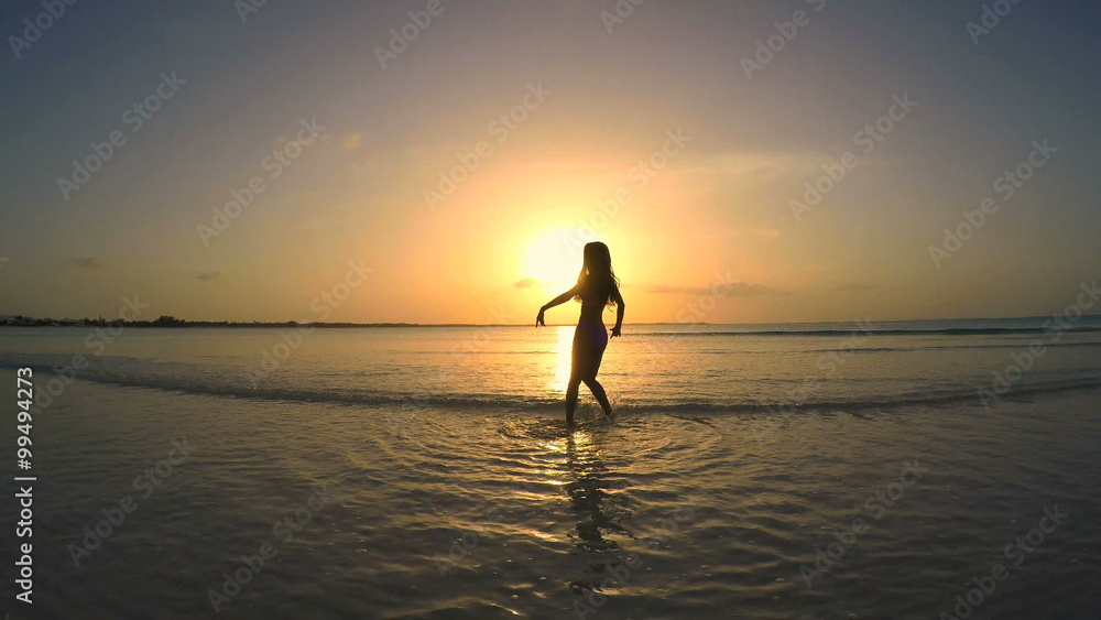 Sunrise silhouette of barefoot ethnic girl dancing on the beach Sunrise silhouette of barefoot ethnic girl dancing on the beach