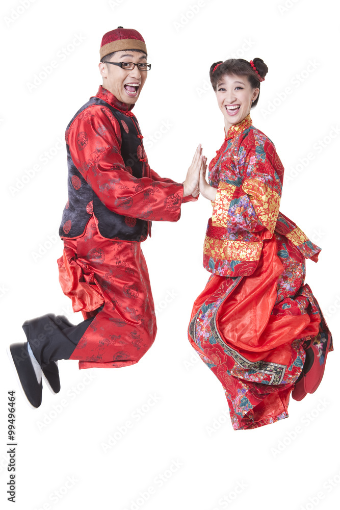 Excited couple in traditional Chinese clothing jumping in mid air