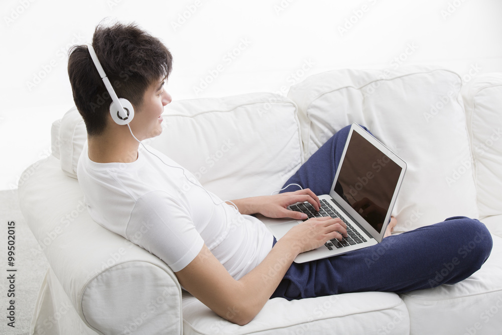 Young man using laptop on couch Young man using laptop on couch