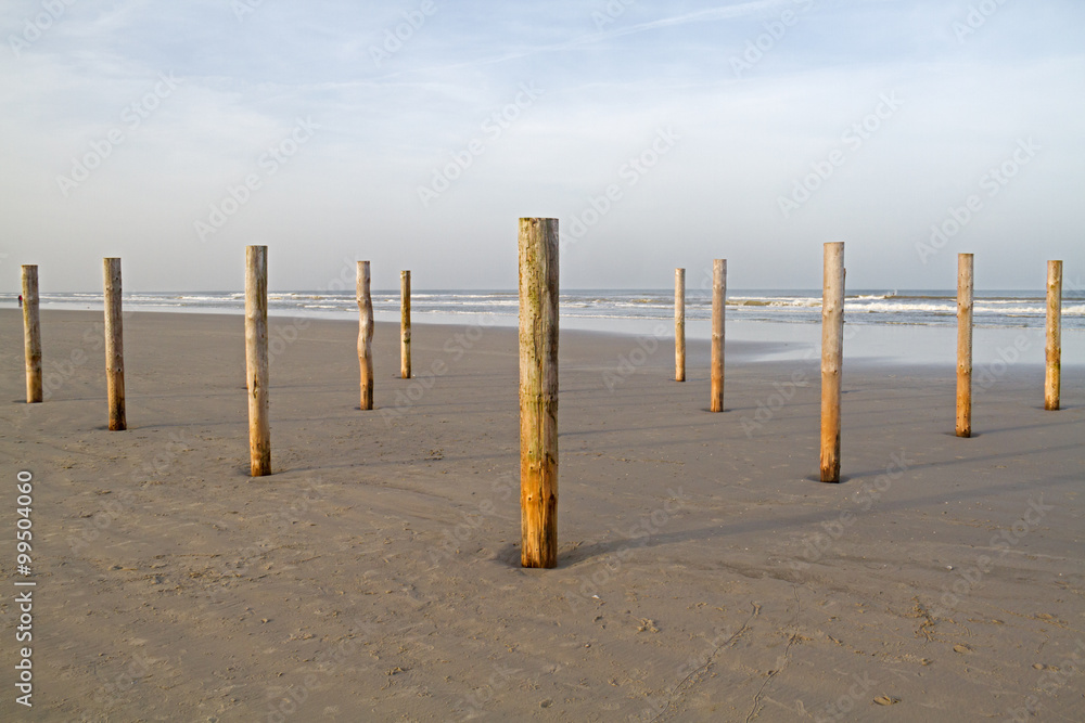 Wooden poles on an empty, deserted beach in winter. Remainders of a beach restaurant