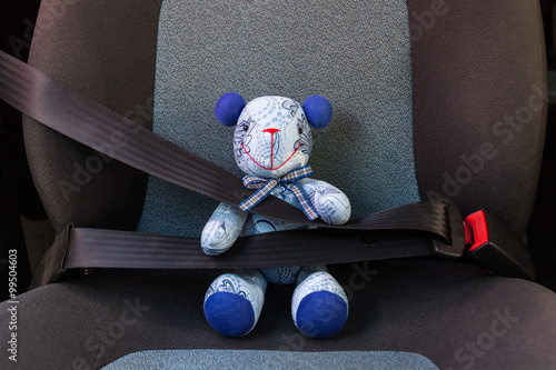 Teddy bear strapped in with seat belt in a car