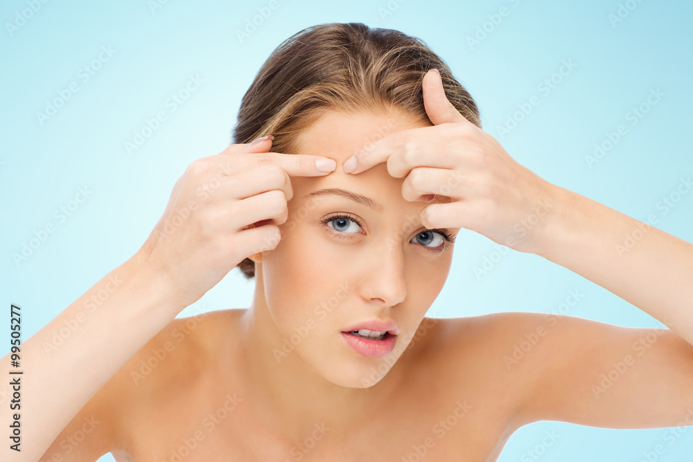 Fototapeta premium young woman squeezing pimple on her face