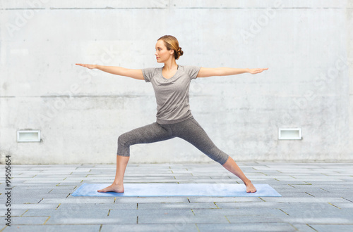 woman making yoga warrior pose on mat