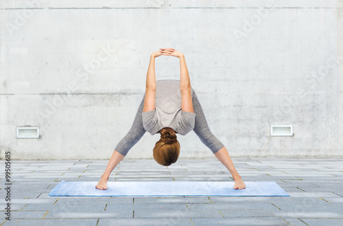 woman making yoga wide-legged forward bend on mat