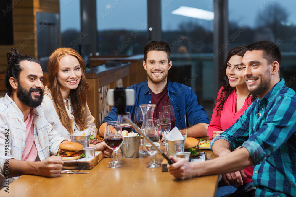 friends taking selfie by smartphone at restaurant