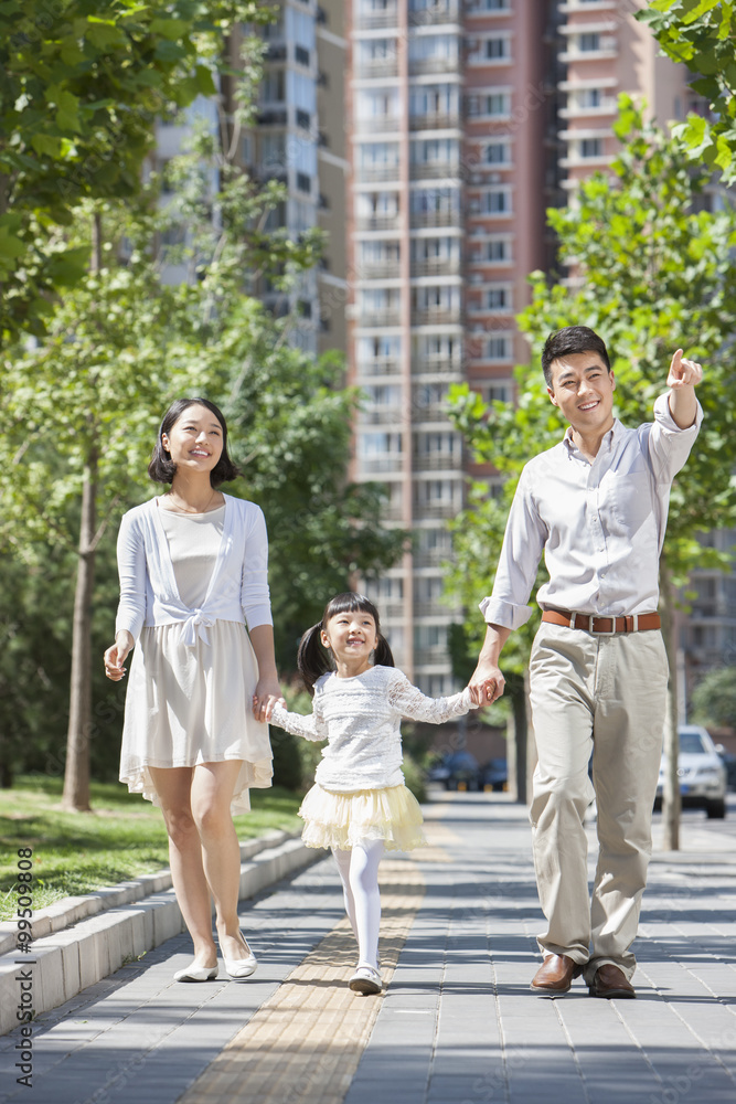 Young parents with daughter strolling on sidewalk hand in hand Young parents with daughter strolling on sidewalk hand in hand