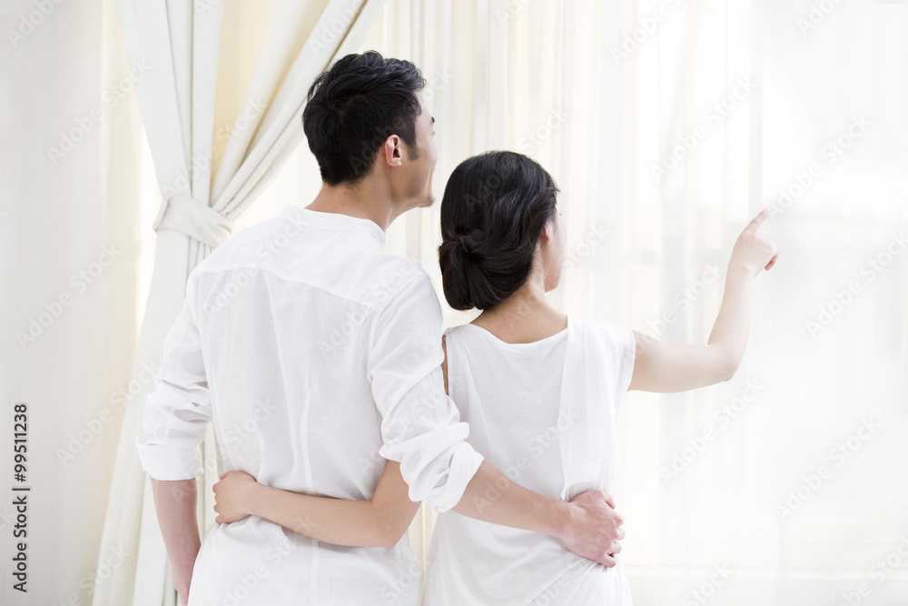 Happy young couple looking out of window Happy young couple looking out of window