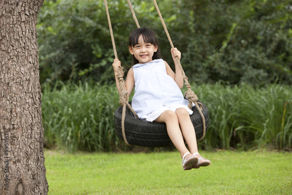 Cheerful little girl playing on a swing