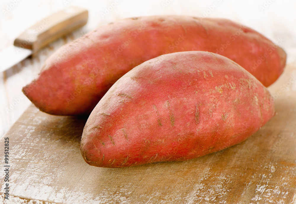 Raw sweet potatoes on a wooden background . Raw sweet potatoes on a wooden background .