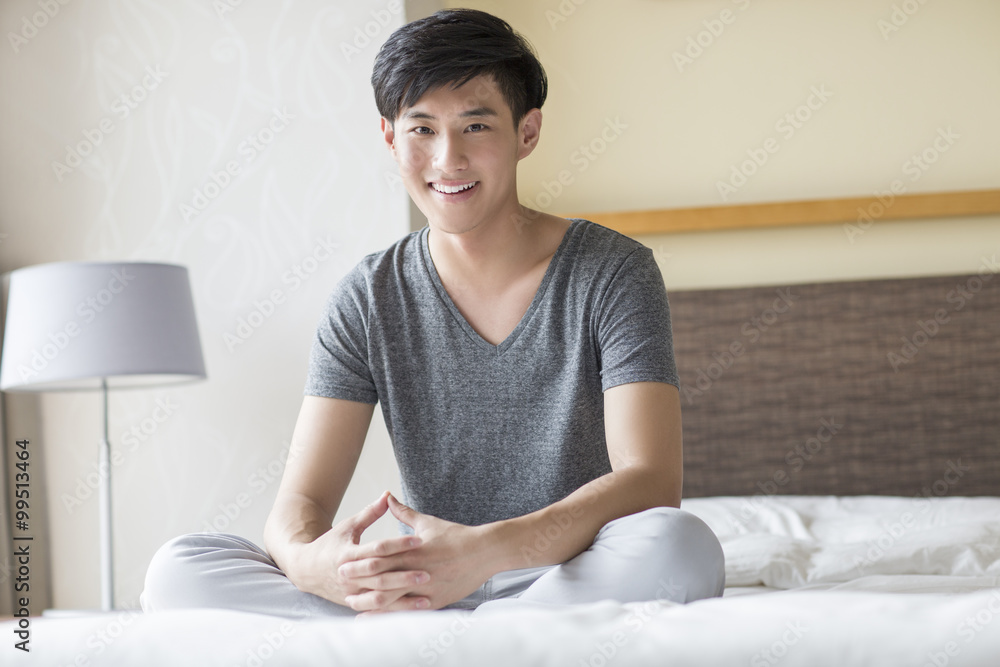 Young man sitting on bed