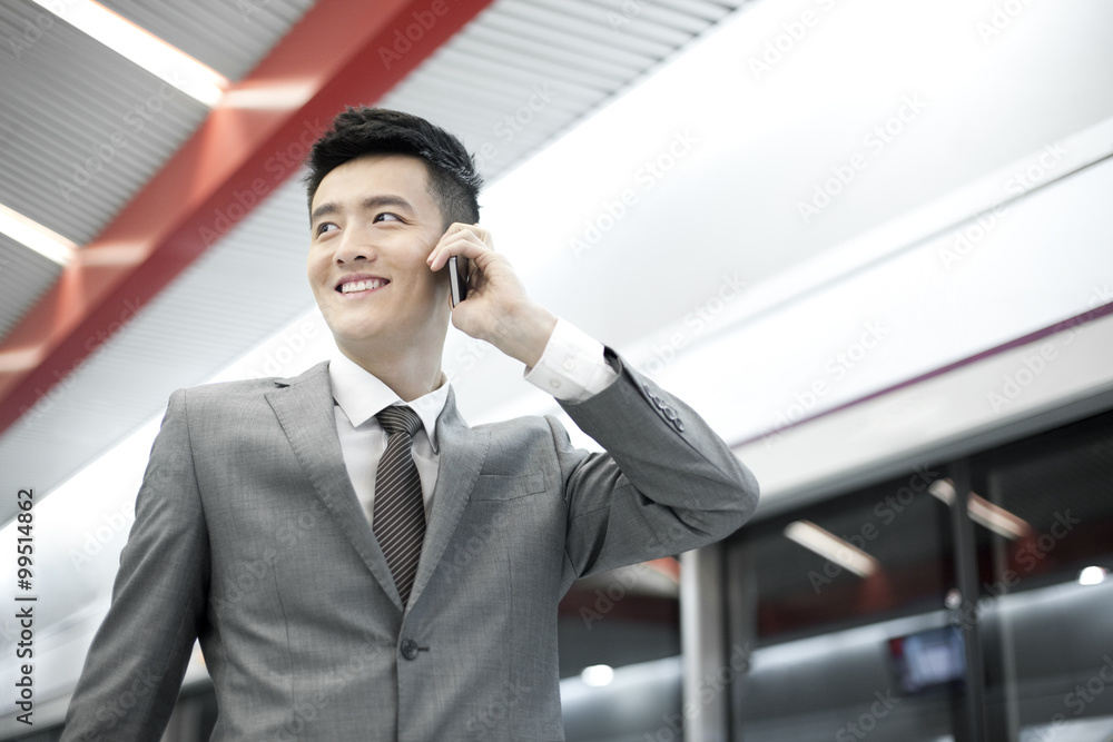 Young businessman on the phone on subway platform Young businessman on the phone on subway platform