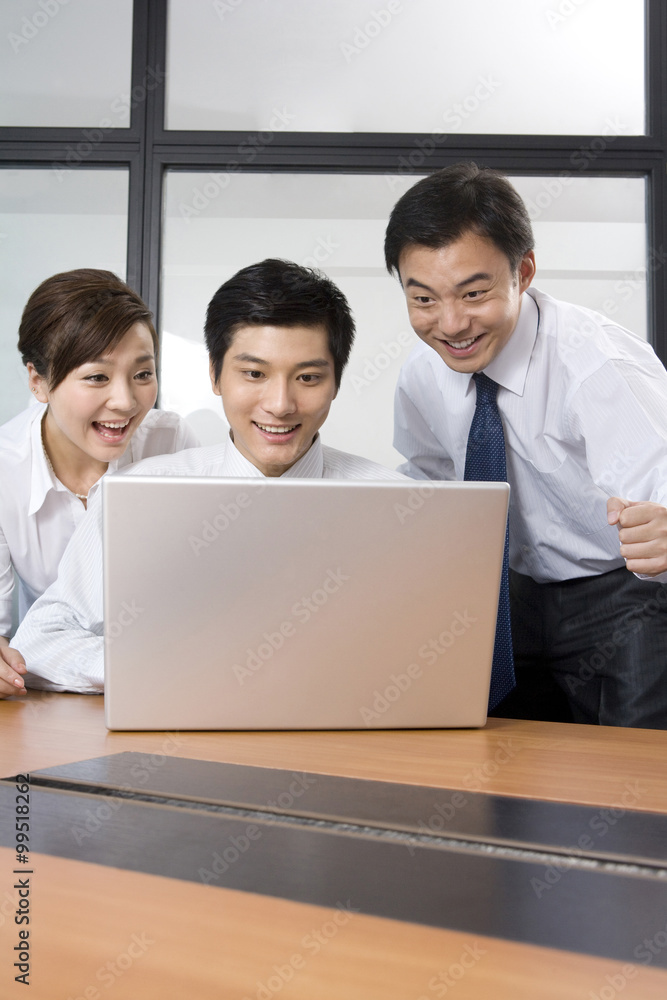 Young businessmen and businesswoman using laptop in office