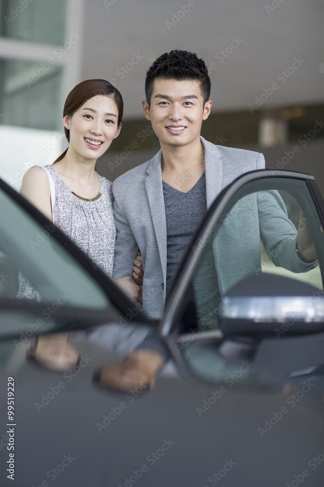 Young couple choosing car in showroom Young couple choosing car in showroom
