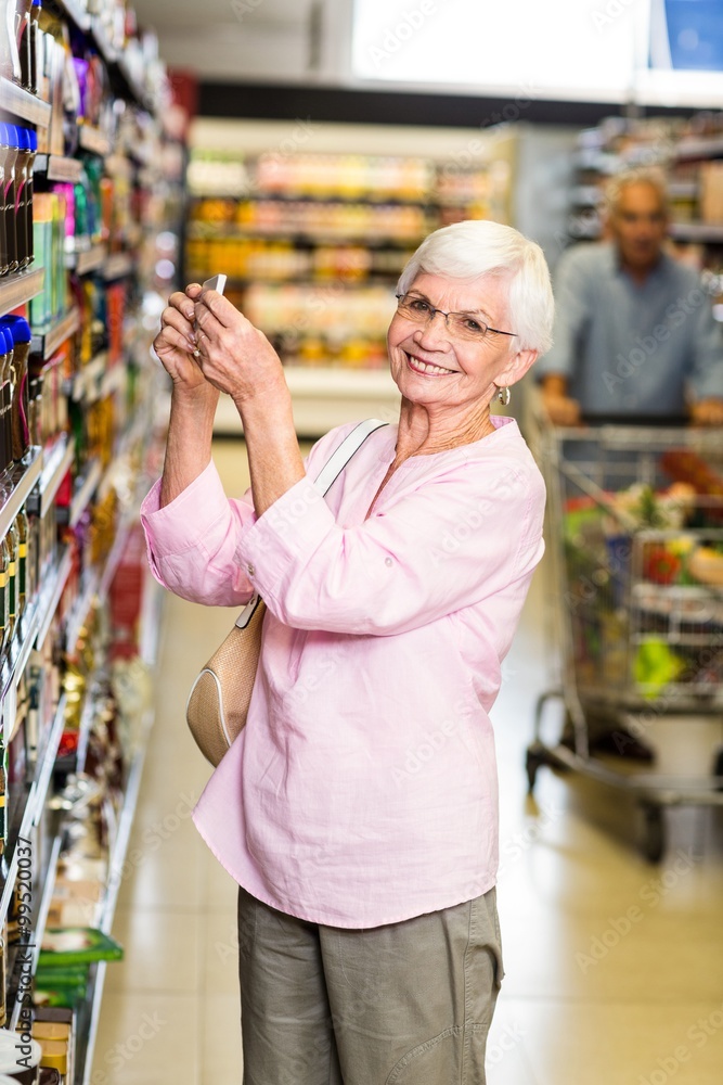 Senior woman taking a picture of product on shelf