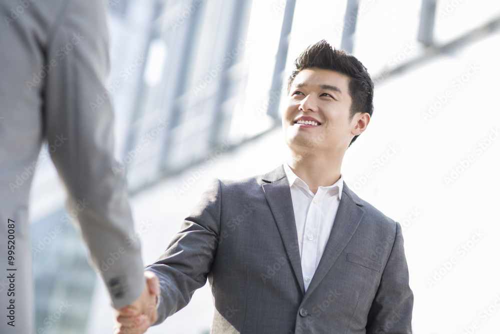 Young business person shaking hands outdoors Young business person shaking hands outdoors