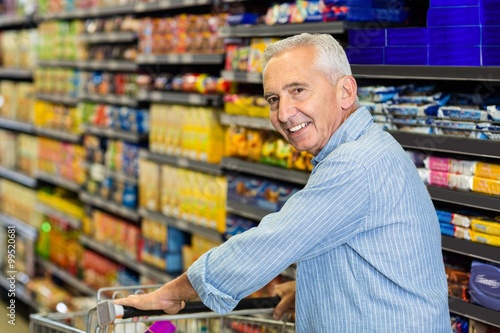 Smiling senior man pushing trolley