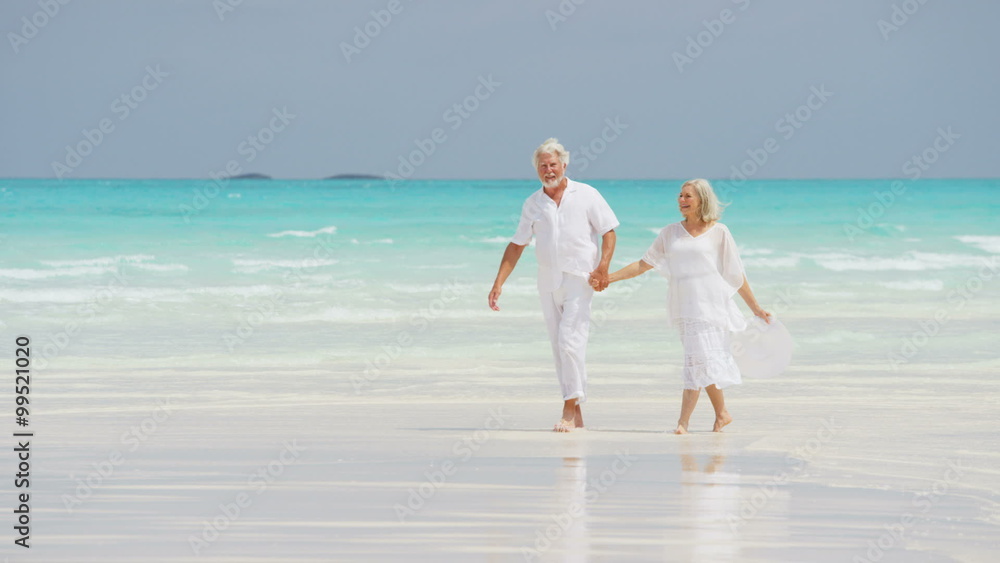 Retired Caucasian couple walking on a Caribbean beach Retired Caucasian couple walking on a Caribbean beach