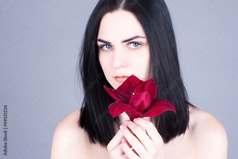 Beautiful young woman with black hair and blue eyes holding red flower Beautiful young woman with black hair and blue eyes holding red flower