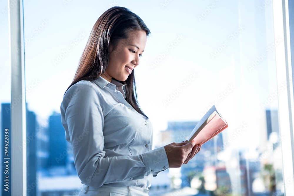 Fototapeta premium Smiling businesswoman reading book