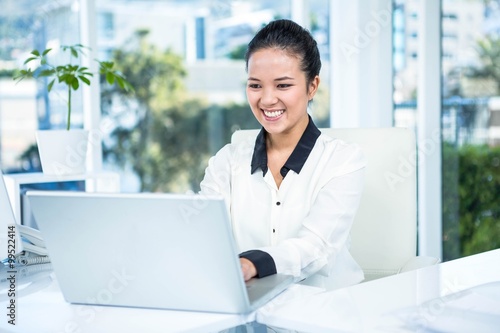 Smiling businesswoman typing on her laptop