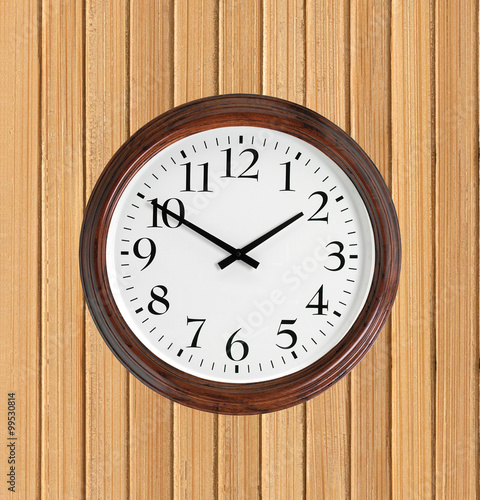Wall clock with wooden frame on wooden planks background