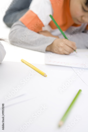 Color pencils in foreground and boy coloring in the background