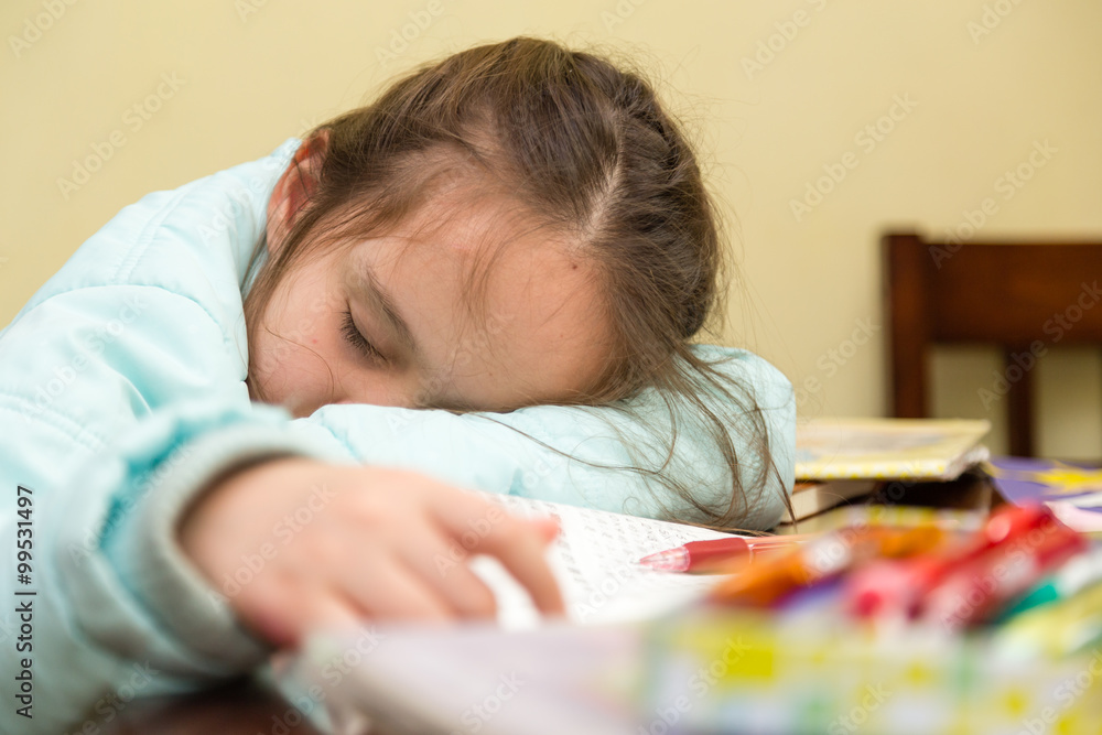 Naklejka premium Young girl falling asleep doing homework