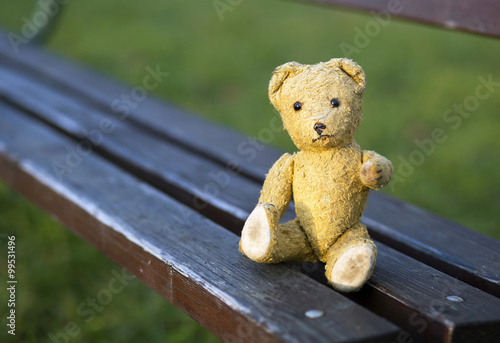 Toy bear sitting on a bench and giving paw 