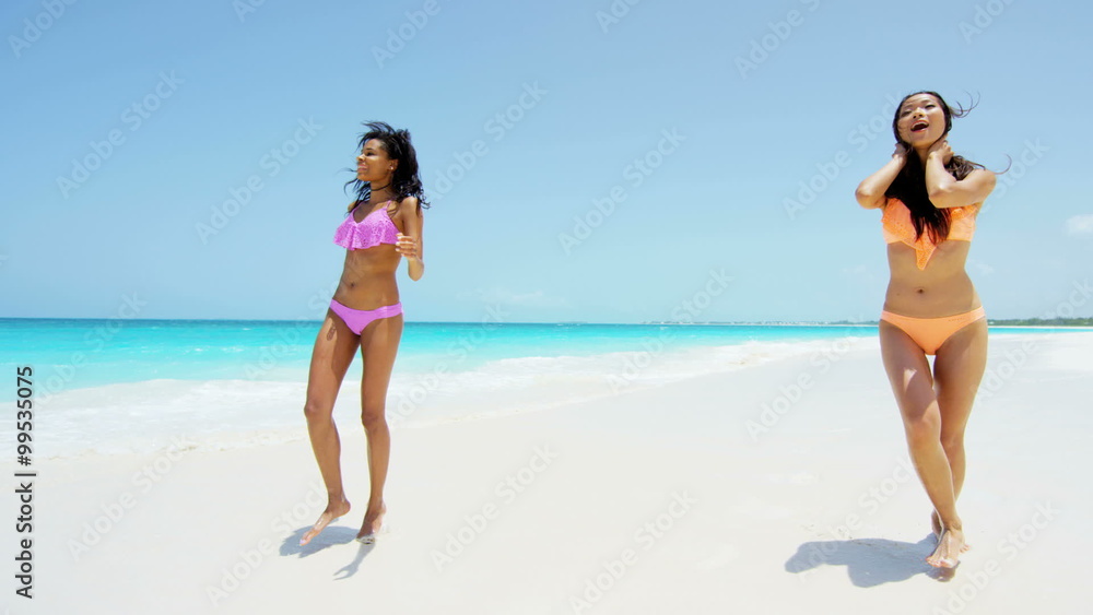 Young multi ethnic girlfriends wearing a bikini on beach Young multi ethnic girlfriends wearing a bikini on beach