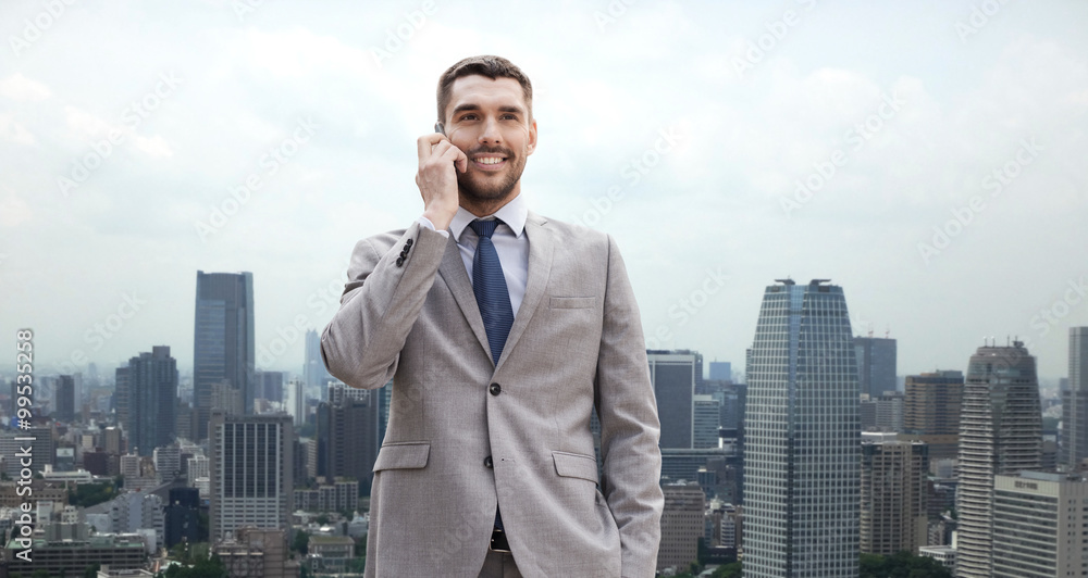 smiling businessman with smartphone in city