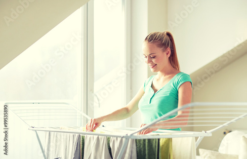 happy woman hanging clothes on dryer at home