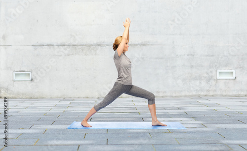 woman making yoga warrior pose on mat outdoors