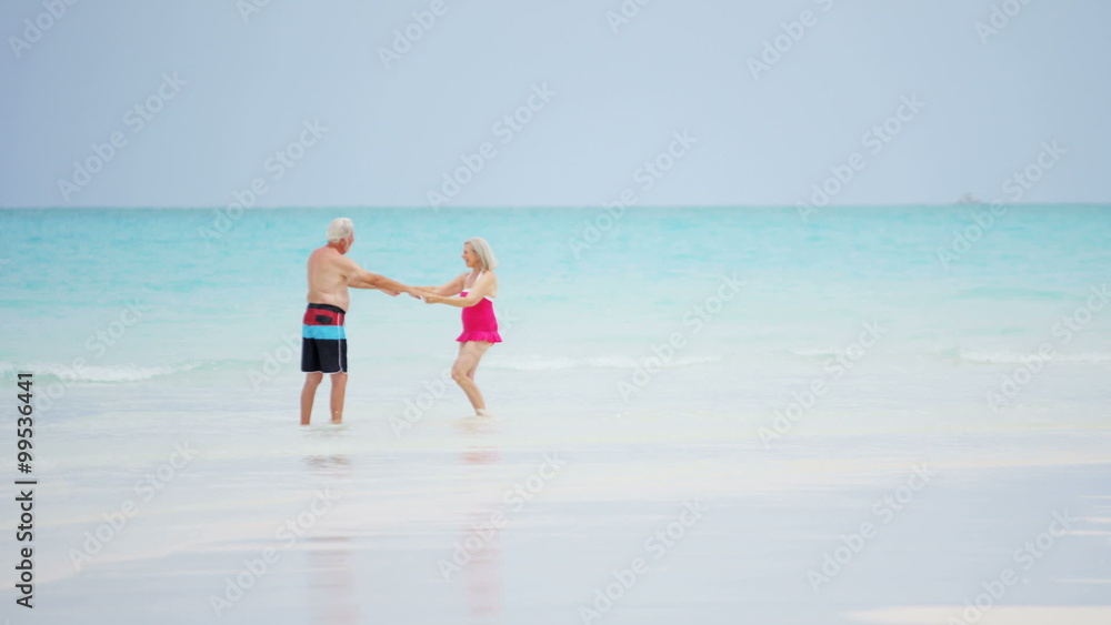 Caucasian senior couple dancing outdoor on a vacation beach in swimwear Caucasian senior couple dancing outdoor on a vacation beach in swimwear