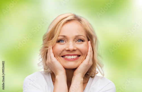 smiling woman in white t-shirt touching her face