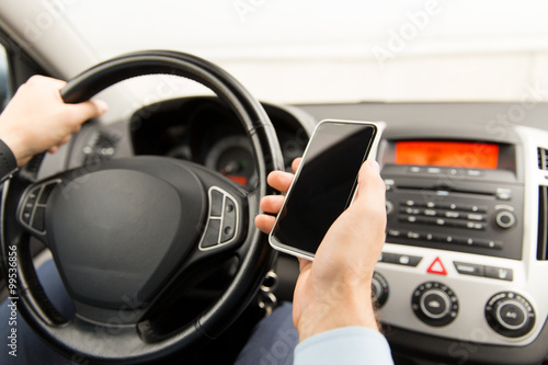 close up of man hand with smartphone driving car