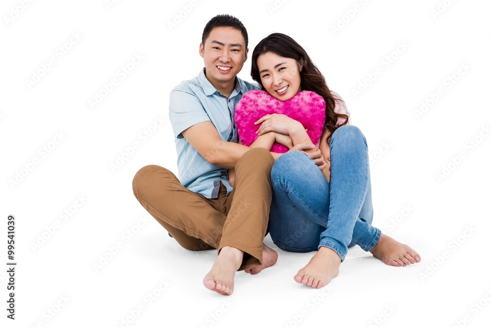 Happy young couple with heart shape pillow Happy young couple with heart shape pillow