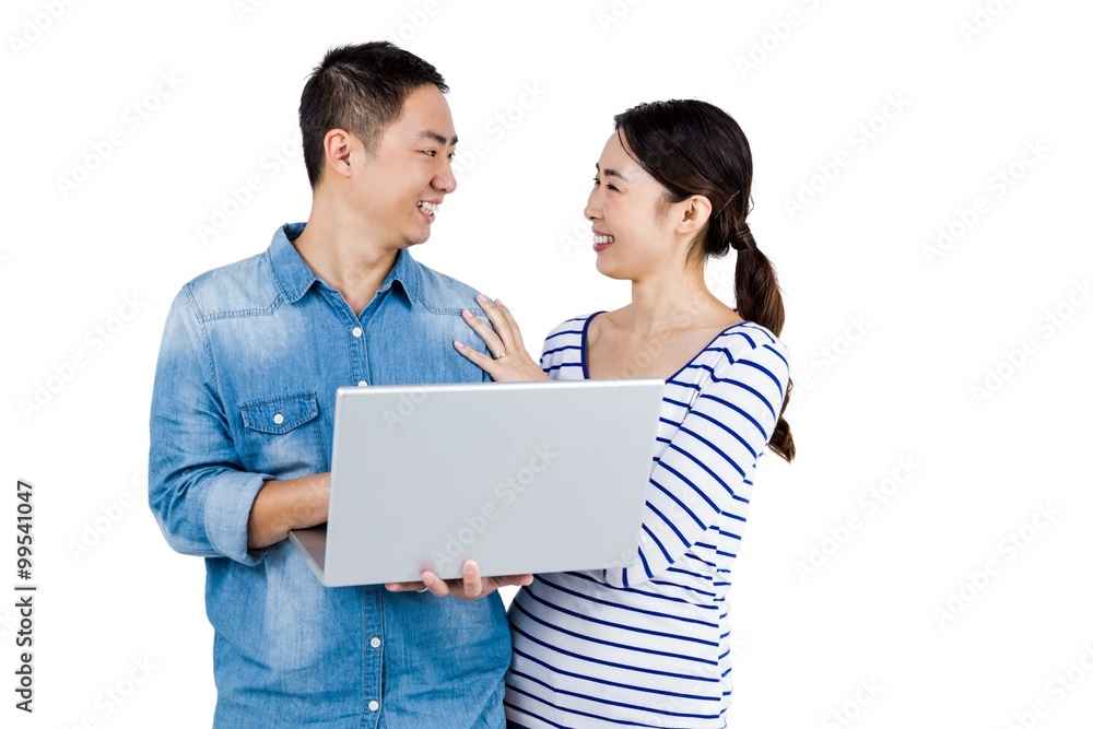 Cheerful couple looking at each other while holding laptop Cheerful couple looking at each other while holding laptop
