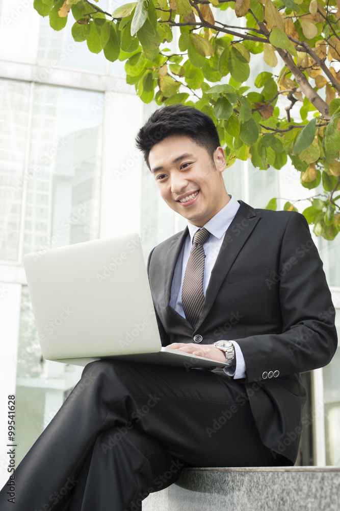 Happy young businessman using laptop outdoors Happy young businessman using laptop outdoors