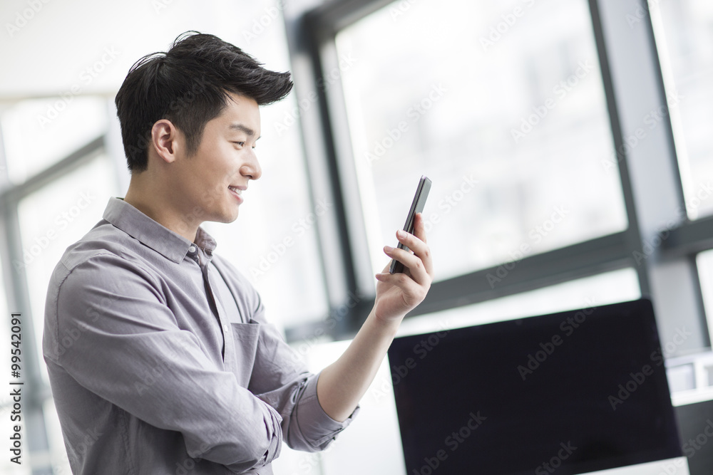Young businessman using smart phone in office Young businessman using smart phone in office
