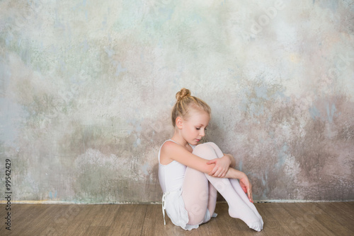 Little ballet dancer sitting white swimsuit, dance, sports, healthy lifestyle, ballet