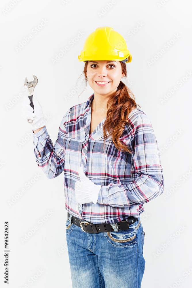 Young woman in construction helmet with wrench Young woman in construction helmet with wrench