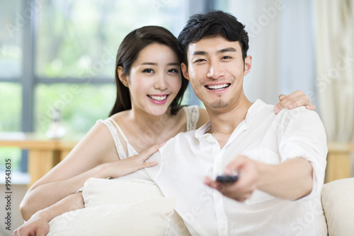 Cheerful young couple watching TV at home