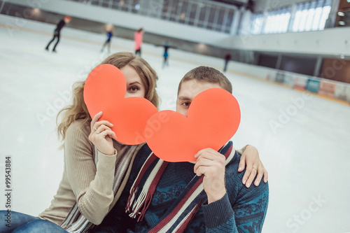 Happy couple on skating rink holding handmade paper heart. © Northern life