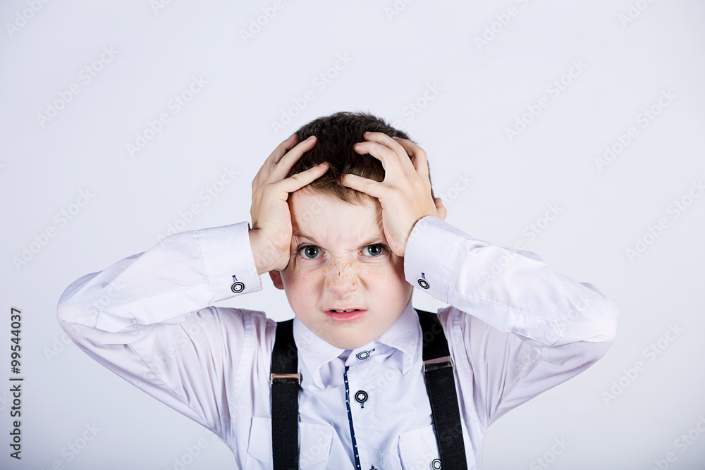 Stressed little boy having problems.Confused little boy with hand on his had over grey background.Stressed little boy having problems.